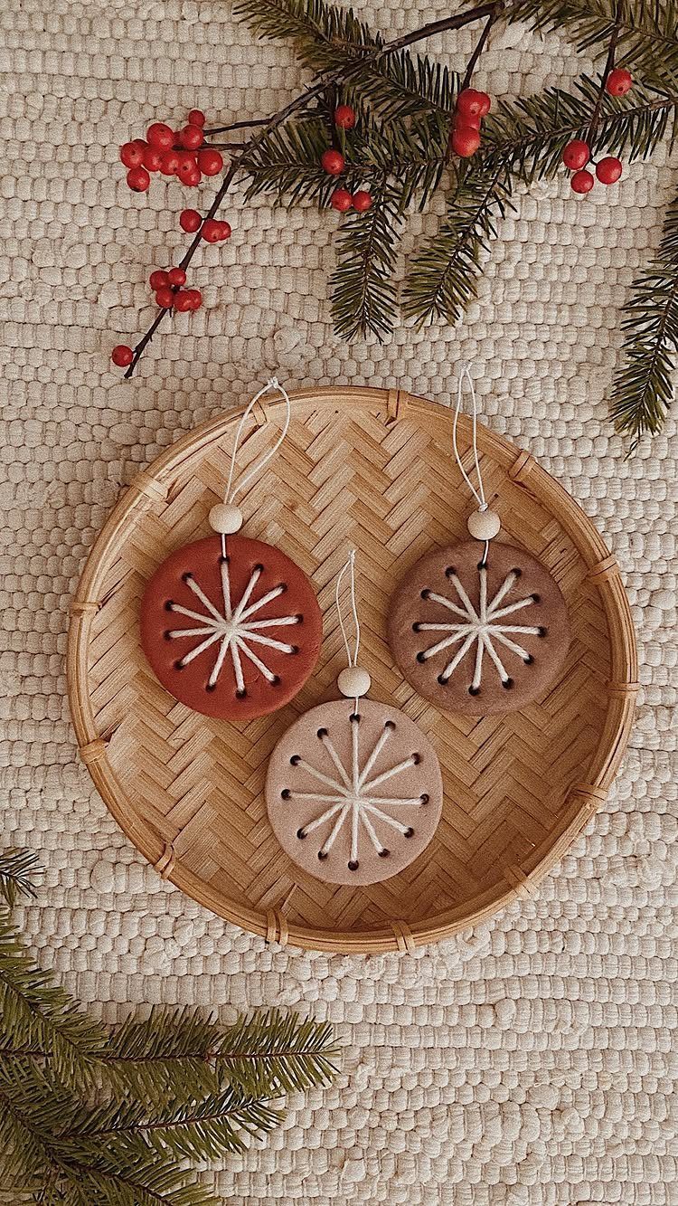 Three painted circular clay ornaments with starburst patterns resting on a woven wooden tray.