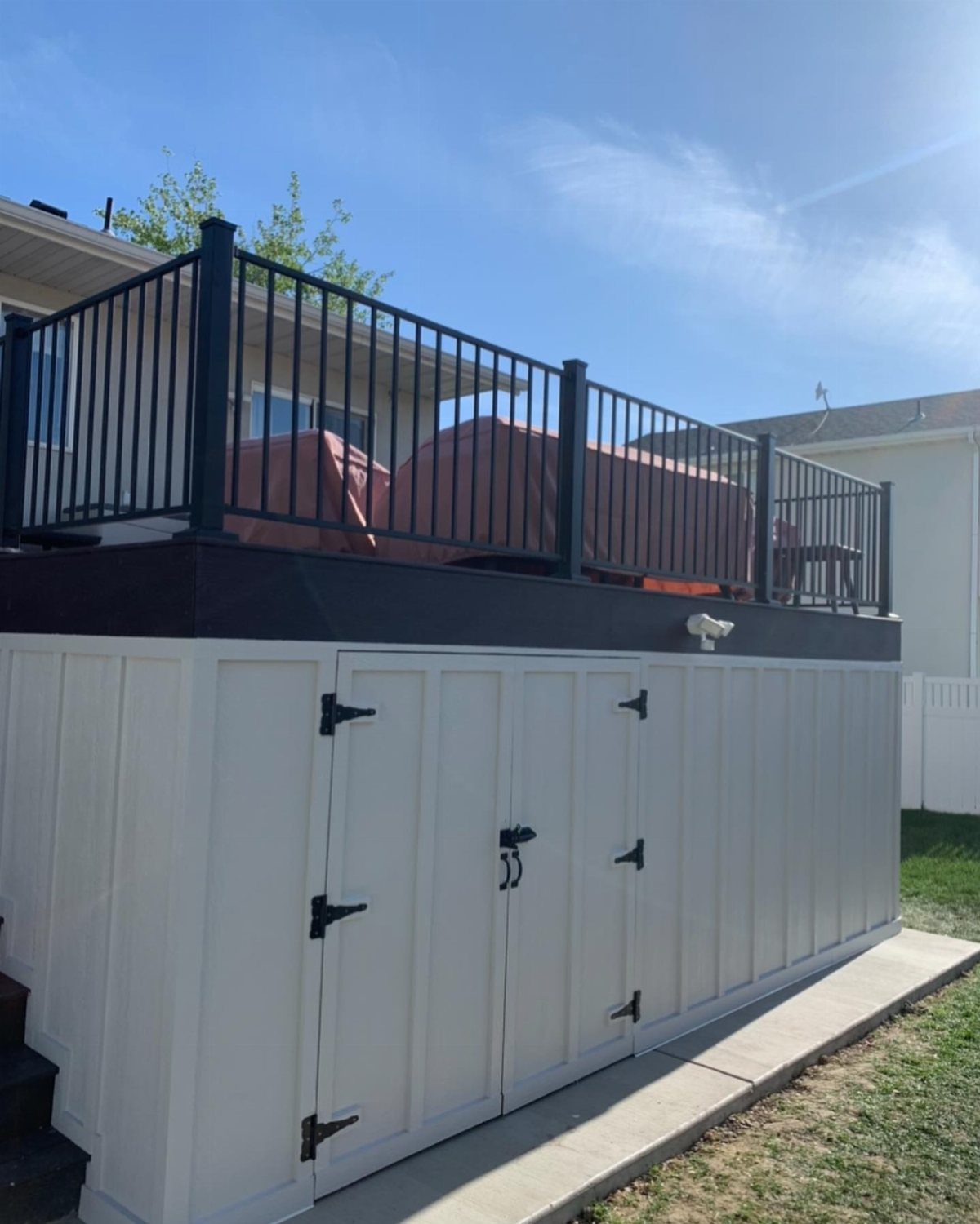 White built-in storage cabinets located underneath a raised wooden deck with black railings.