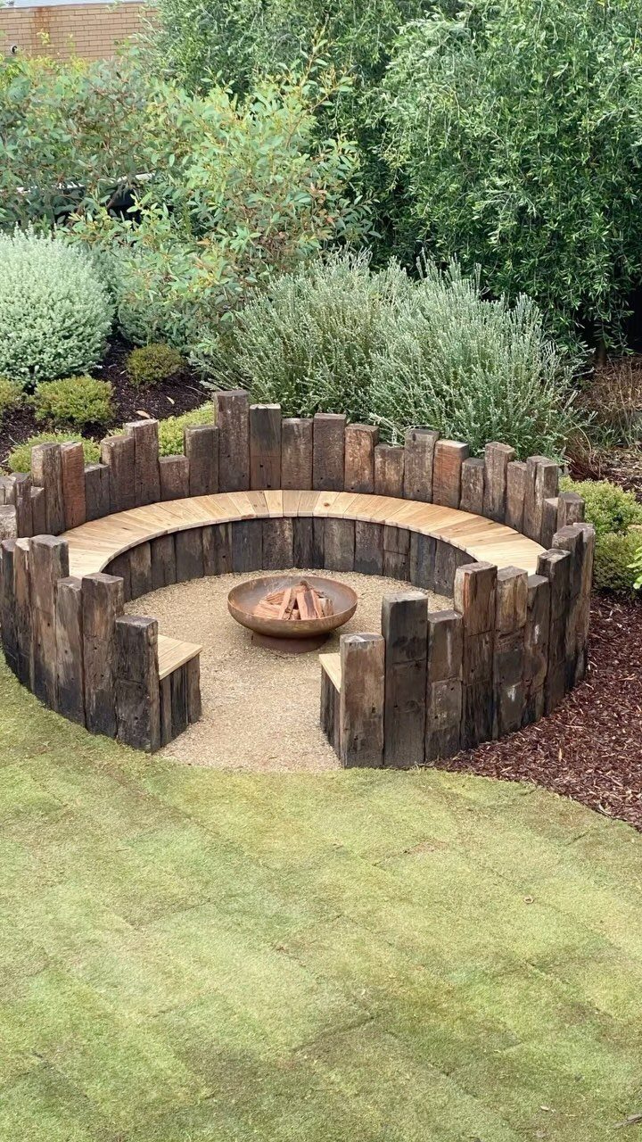 Circular wooden built-in bench surrounding a central fire pit in a landscaped backyard garden.
