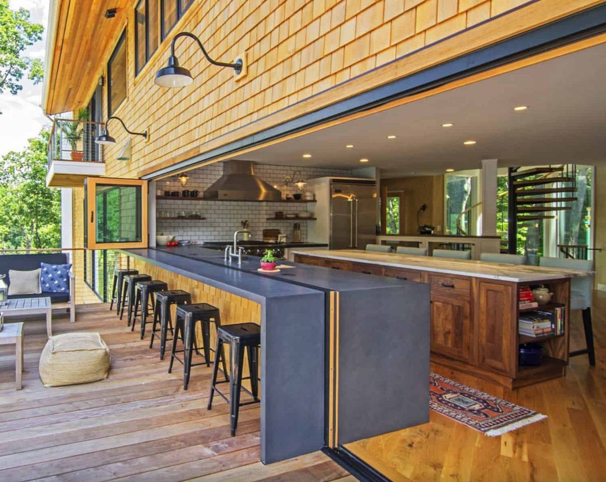 Barndominium Indoor Outdoor Kitchen: 8 Ideas That Erase the Wall 1 A long dark gray stone counter transitions from an indoor kitchen to an outdoor wooden deck.