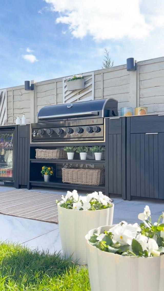 Black outdoor kitchen unit with a built-in grill and storage baskets under open shelving.