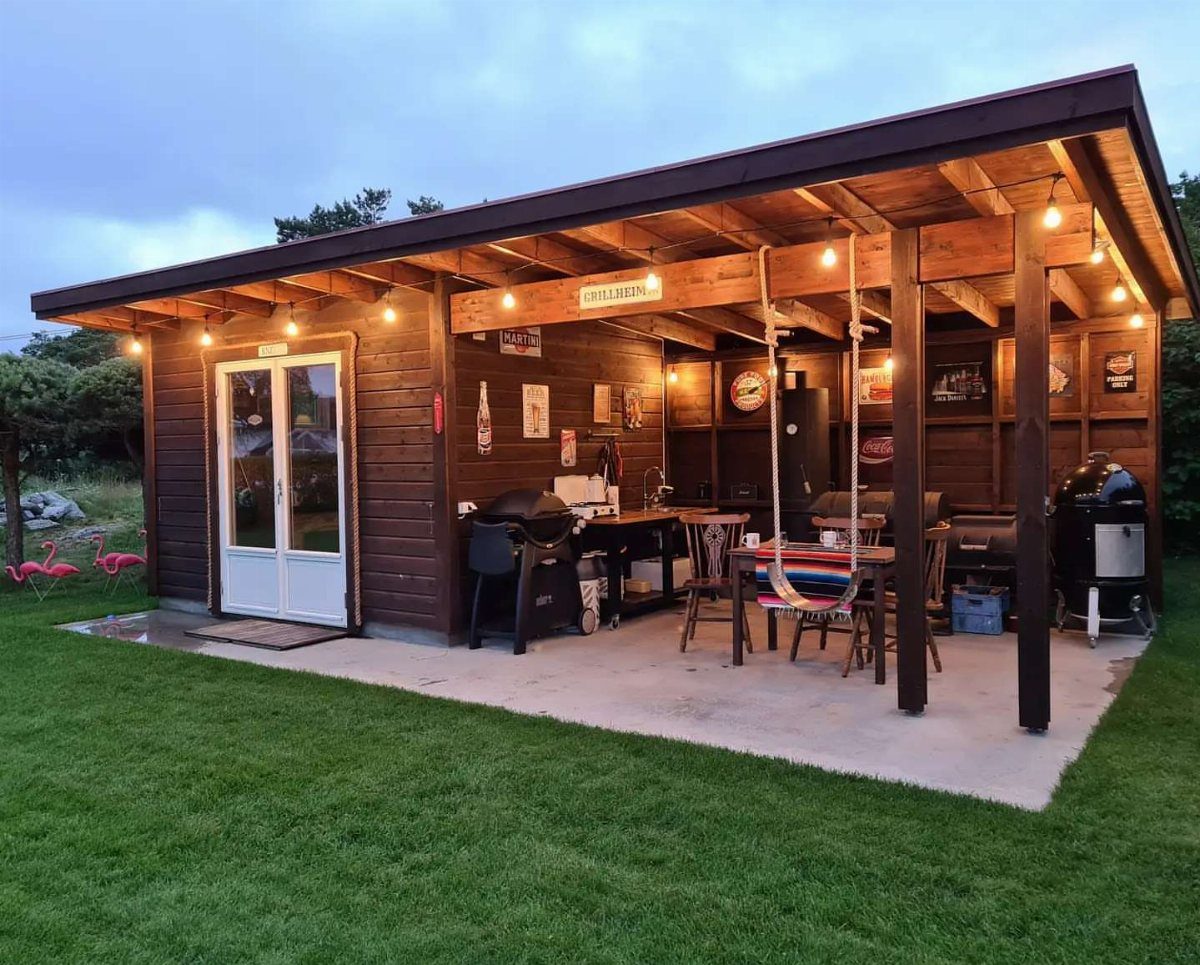 A wooden shed converted into a cozy outdoor BBQ and dining area with string lights.
