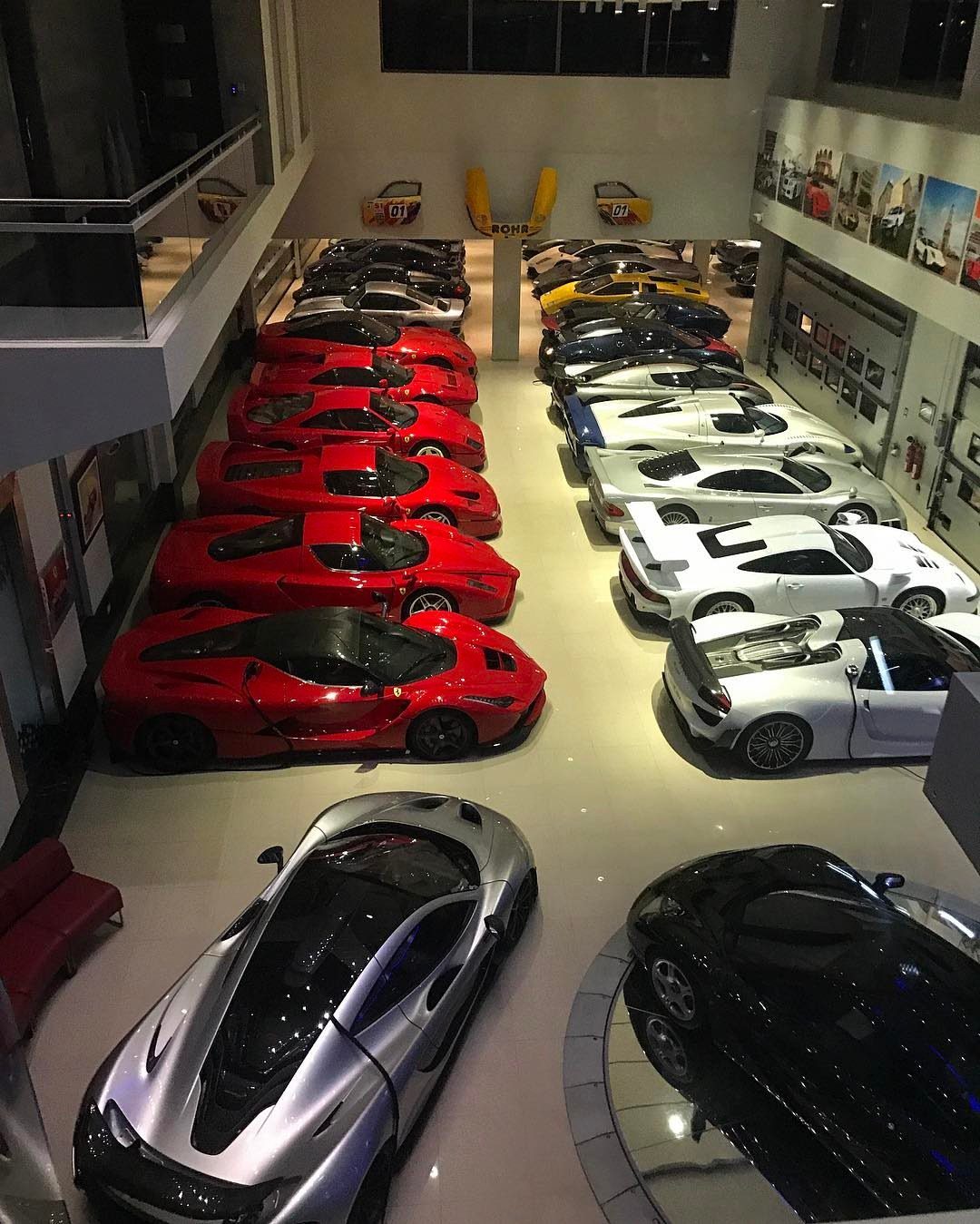 Luxury sports cars parked in a large, brightly lit, high-end indoor automotive gallery showroom.