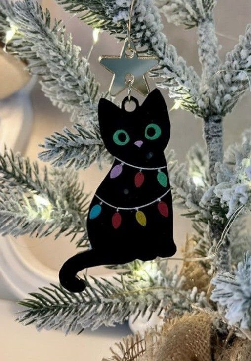 Black Cat Christmas: 8 Photo Ideas for the Holidays 7 Black cat ornament with colorful lights hanging on a snowy Christmas tree branch.