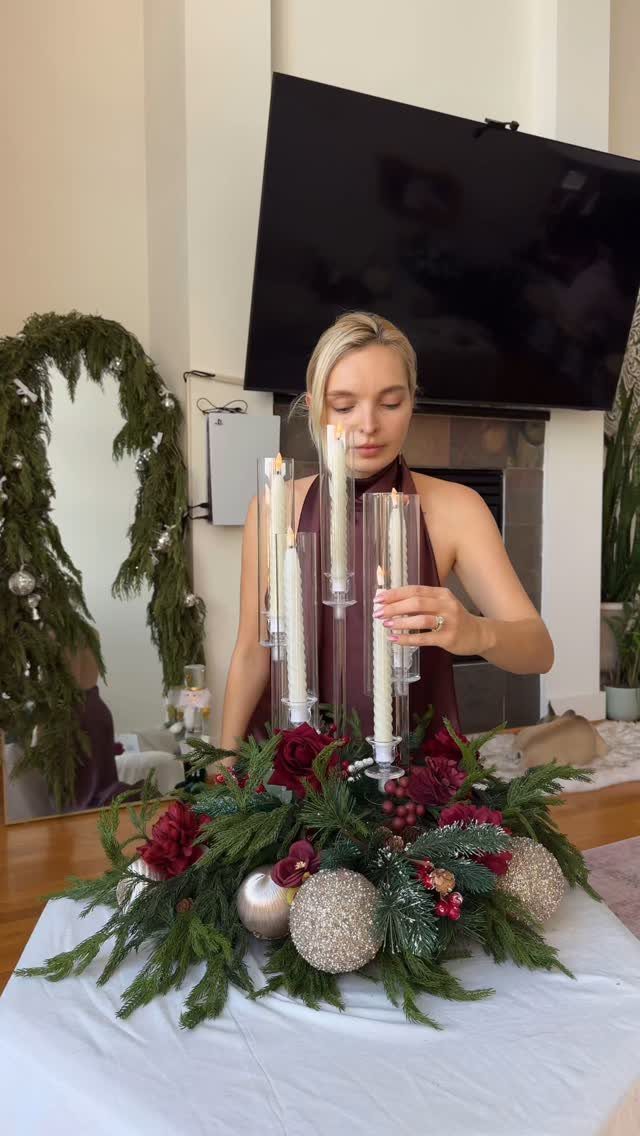 Burgundy Tree Decor: 9 Ideas Borrowed from High-End Design 8 A woman arranging a centerpiece with green foliage, silver ornaments, and burgundy flowers.