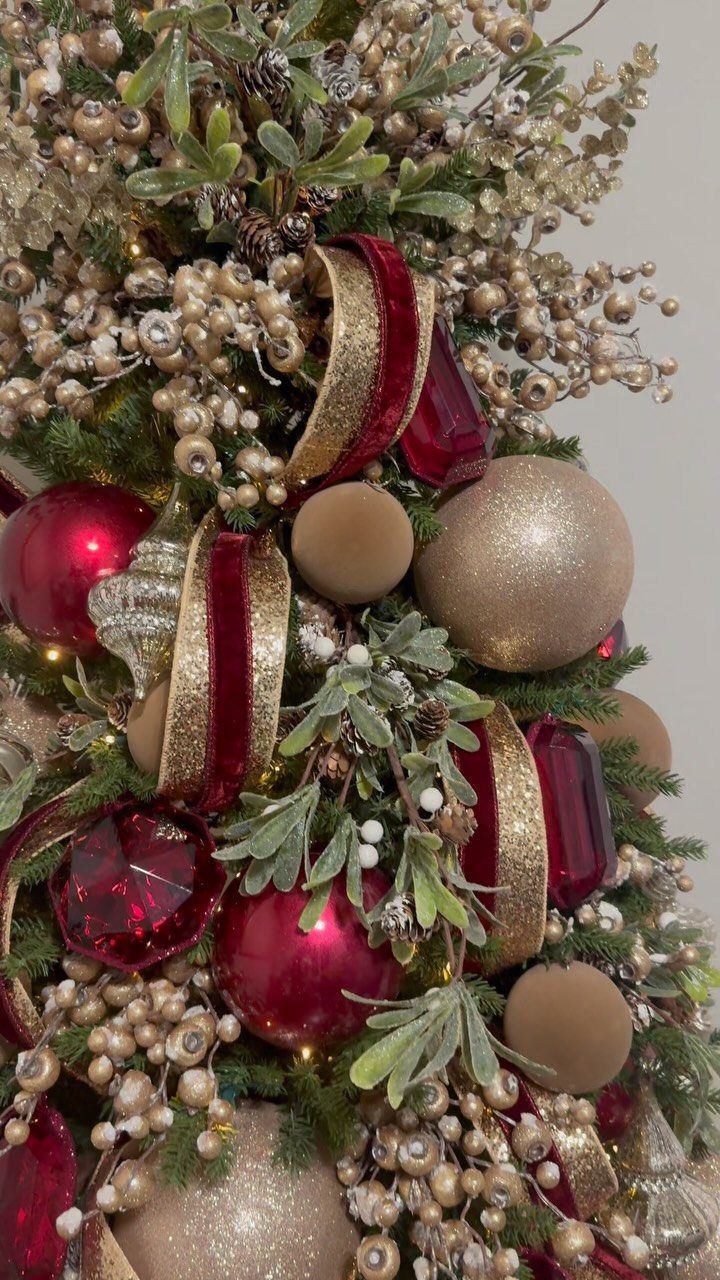 Burgundy Tree Decor: 9 Ideas Borrowed from High-End Design 4 Burgundy velvet ribbons with gold edges woven through a decorated Christmas tree with gold ornaments.