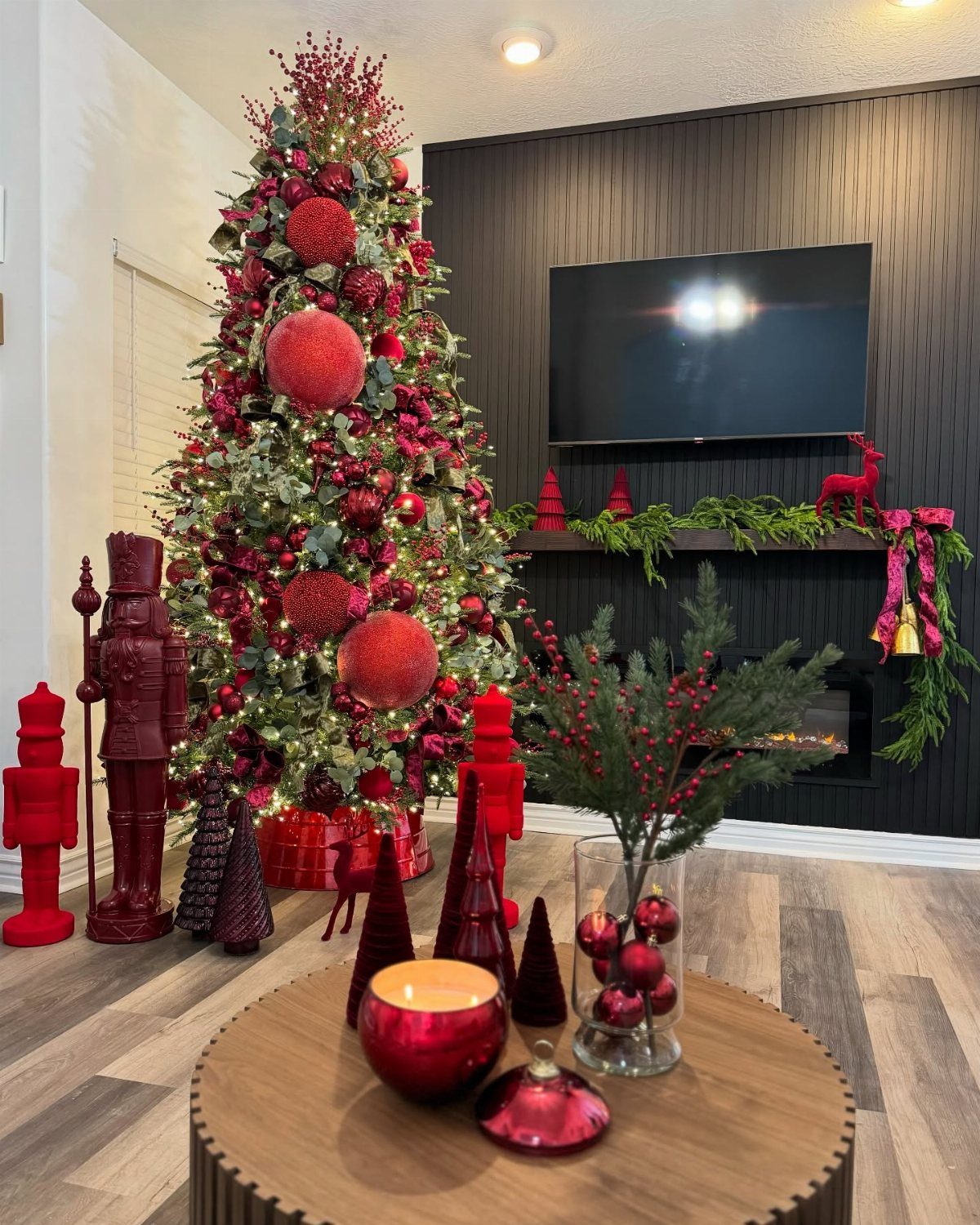 Burgundy Tree Decor: 9 Ideas Borrowed from High-End Design 9 Decorated Christmas tree with red ornaments and berries next to red nutcrackers and a coffee table.
