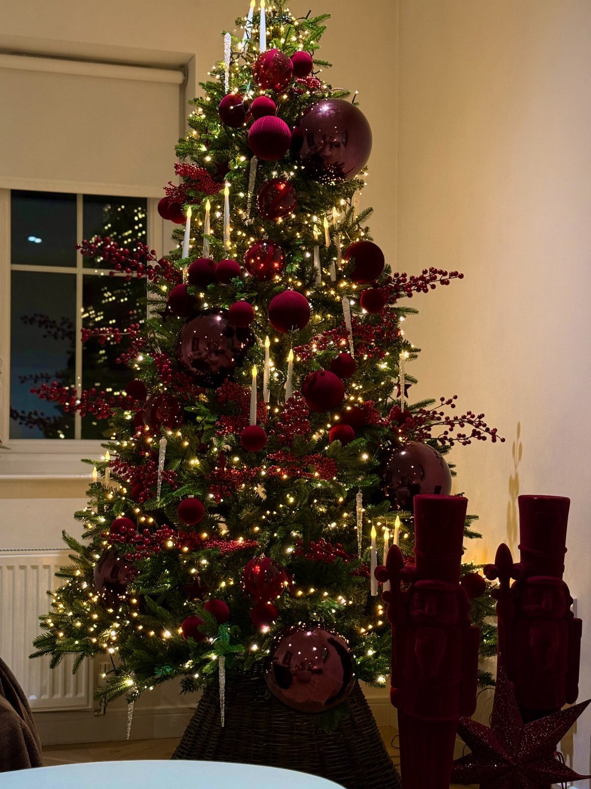Burgundy Tree Decor: 9 Ideas Borrowed from High-End Design 2 A Christmas tree decorated with burgundy ornaments, red berries, and warm glowing lights.