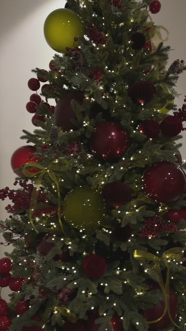 Burgundy Tree Decor: 9 Ideas Borrowed from High-End Design 7 A decorated Christmas tree with burgundy ornaments, gold ribbons, and small white lights.
