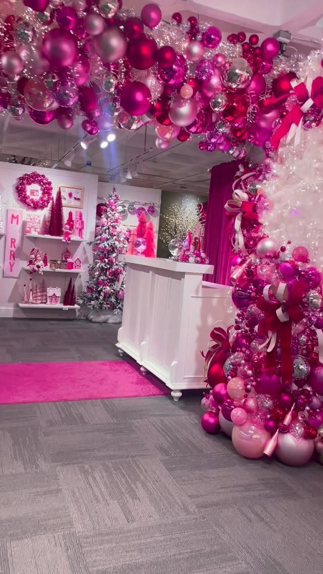 9 Ceiling Christmas Decor Ideas for 2026 3 Pink and magenta Christmas ornaments hanging from the ceiling and clustered around a white counter.