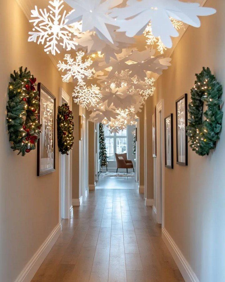 9 Ceiling Christmas Decor Ideas for 2026 7 Large white paper snowflakes hanging from a ceiling in a decorated hallway.
