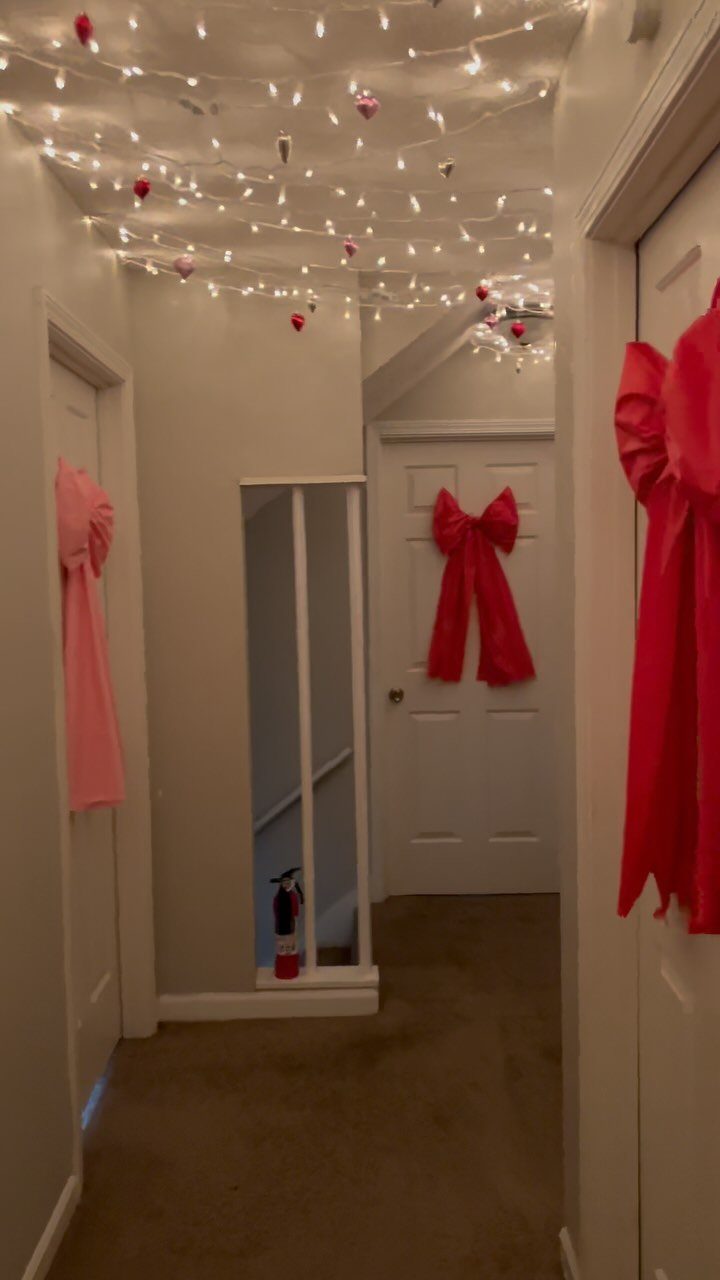 9 Ceiling Christmas Decor Ideas for 2026 1 White string lights draped across a ceiling with small red ornaments hanging from them.