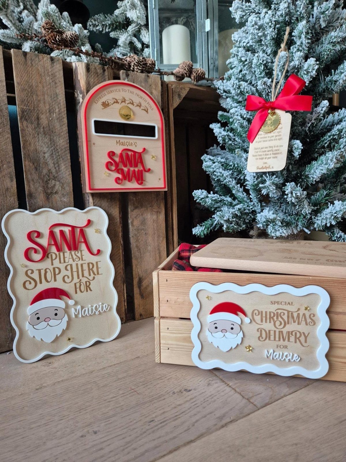25 Christmas Art and Craft Ideas for Cards, Ornaments, and Decor 22 A decorated wooden crate with Santa signs sitting next to a snowy Christmas tree.