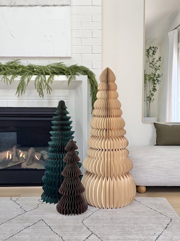 25 Christmas Art and Craft Ideas for Cards, Ornaments, and Decor 2 Three honeycomb paper trees in tan, brown, and green standing on a rug.