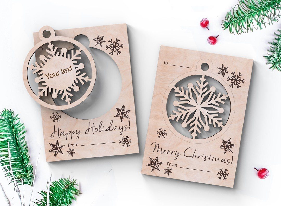 25 Christmas Art and Craft Ideas for Cards, Ornaments, and Decor 19 Two wooden Christmas cards with snowflake silhouette cutouts and festive printed text on white background.