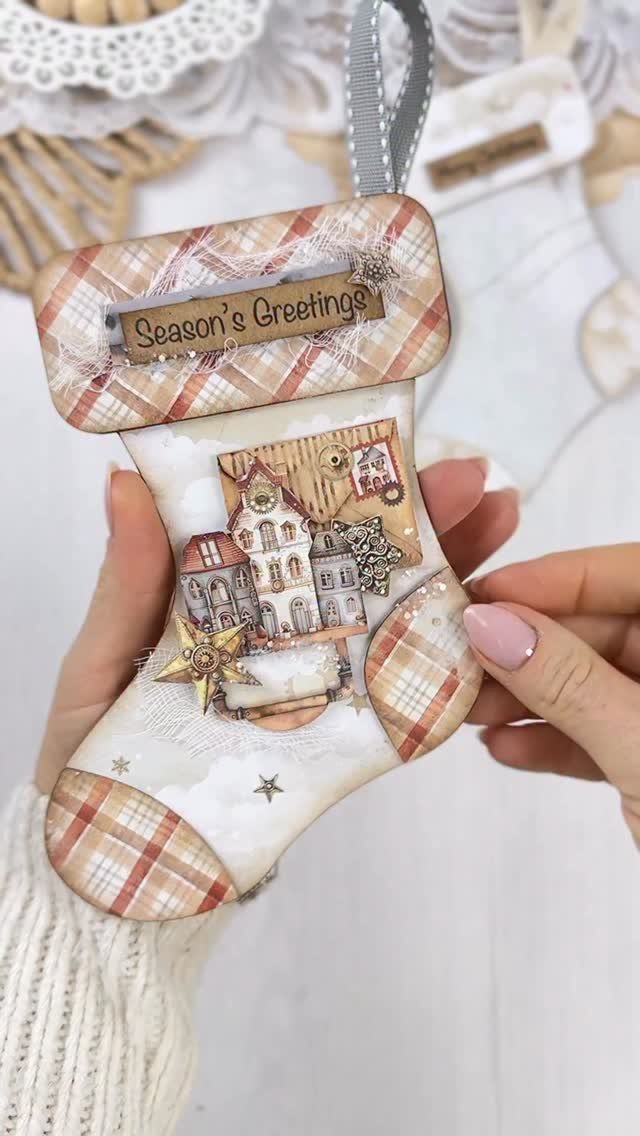 25 Christmas Art and Craft Ideas for Cards, Ornaments, and Decor 7 Hands holding a decorated handmade Christmas stocking card with vintage house illustrations.