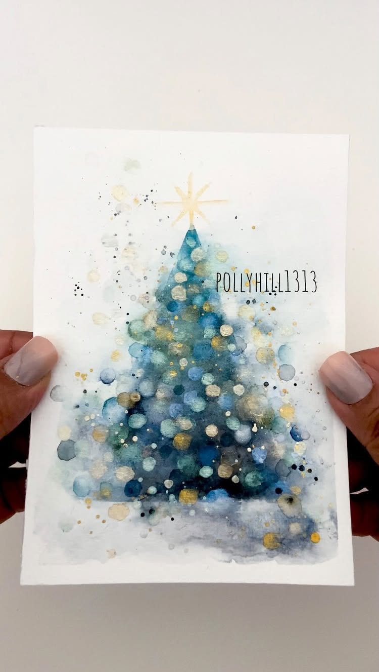 25 Christmas Art and Craft Ideas for Cards, Ornaments, and Decor 1 Hands holding a handmade watercolor Christmas card with a blue and gold tree design.