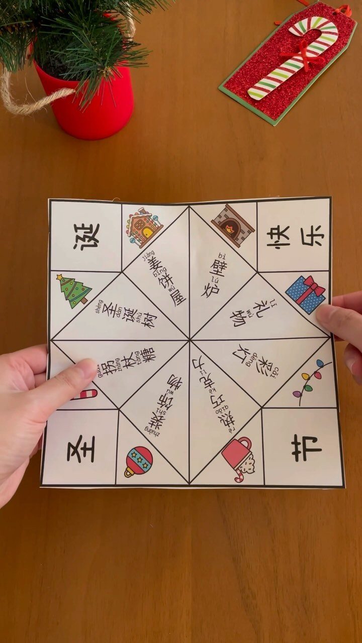 25 Christmas Art and Craft Ideas for Cards, Ornaments, and Decor 25 Hands holding a paper Christmas fortune teller with festive drawings on a wooden table.