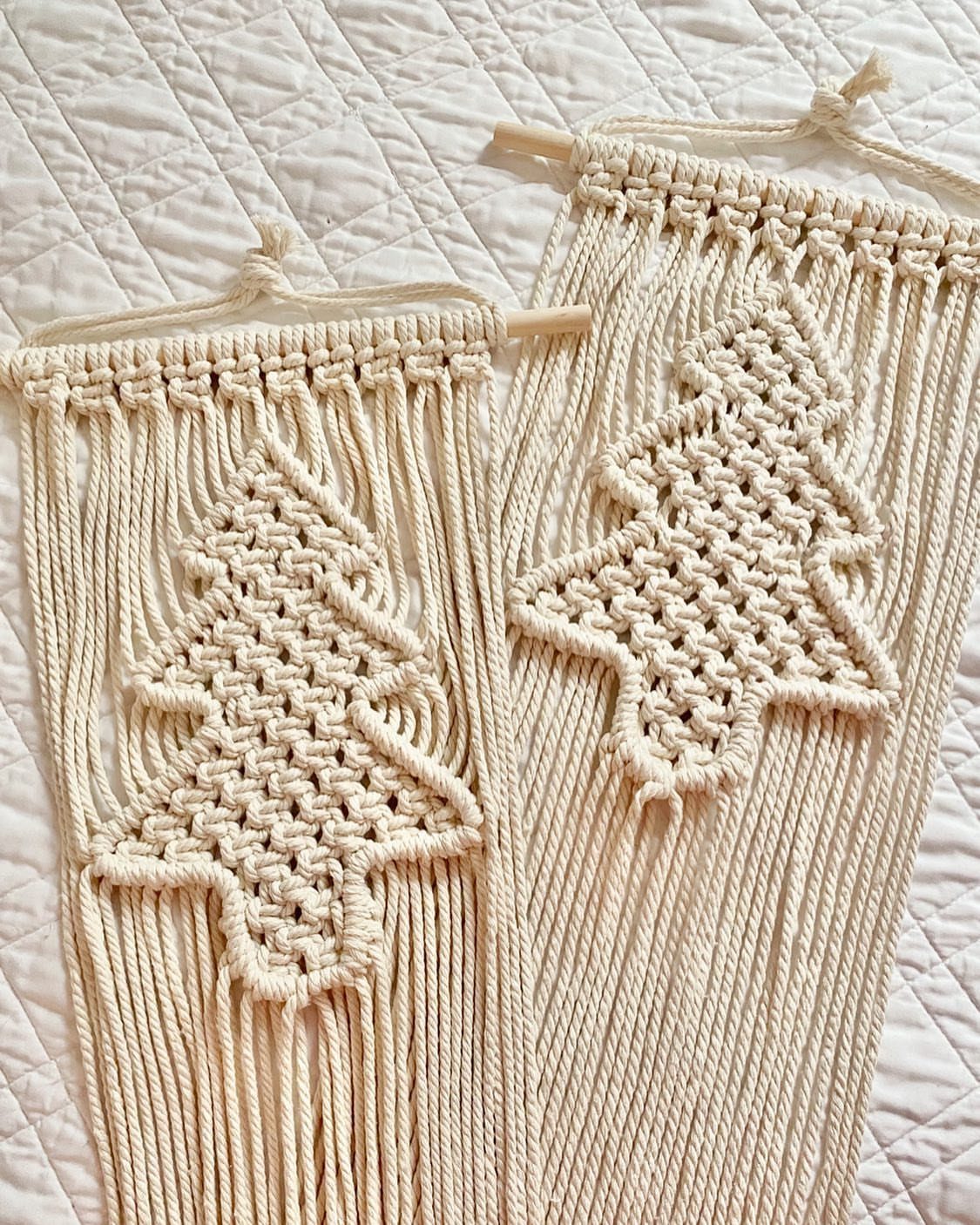 25 Christmas Art and Craft Ideas for Cards, Ornaments, and Decor 23 Two macrame Christmas tree wall hangings made of cream cotton cord on wooden dowels.
