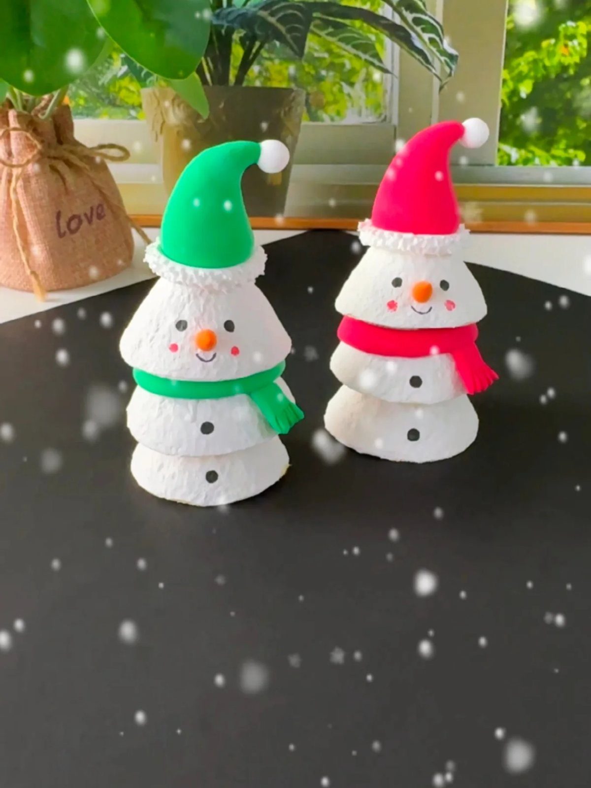 25 Christmas Art and Craft Ideas for Cards, Ornaments, and Decor 8 Two egg carton snowmen with colorful hats and scarves sitting on a black surface.