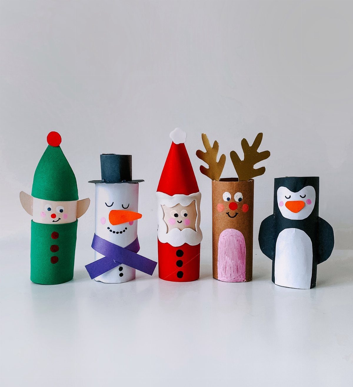 25 Christmas Art and Craft Ideas for Cards, Ornaments, and Decor 16 Five handmade Christmas characters crafted from toilet paper rolls standing in a row.