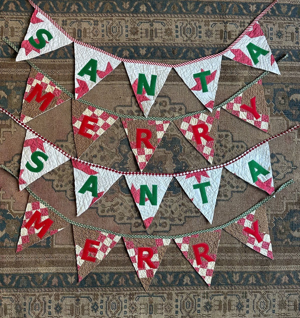 Christmas Decorations with Pinecones: 17 Ideas for Your Home 9 White patterned fabric pennant garland spelling Santa Merry on a patterned rug.