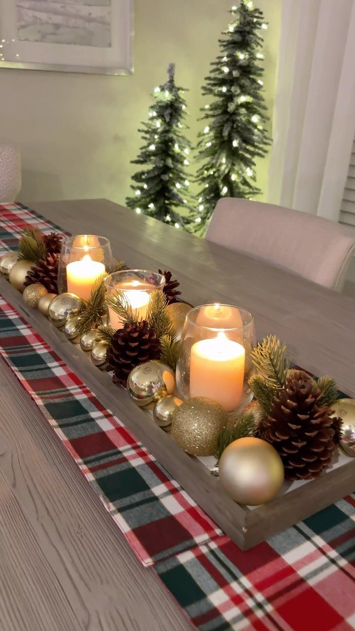 Christmas Decorations with Pinecones: 17 Ideas for Your Home 10 A wooden dough bowl filled with pinecones, gold ornaments, and lit candles on a plaid runner.