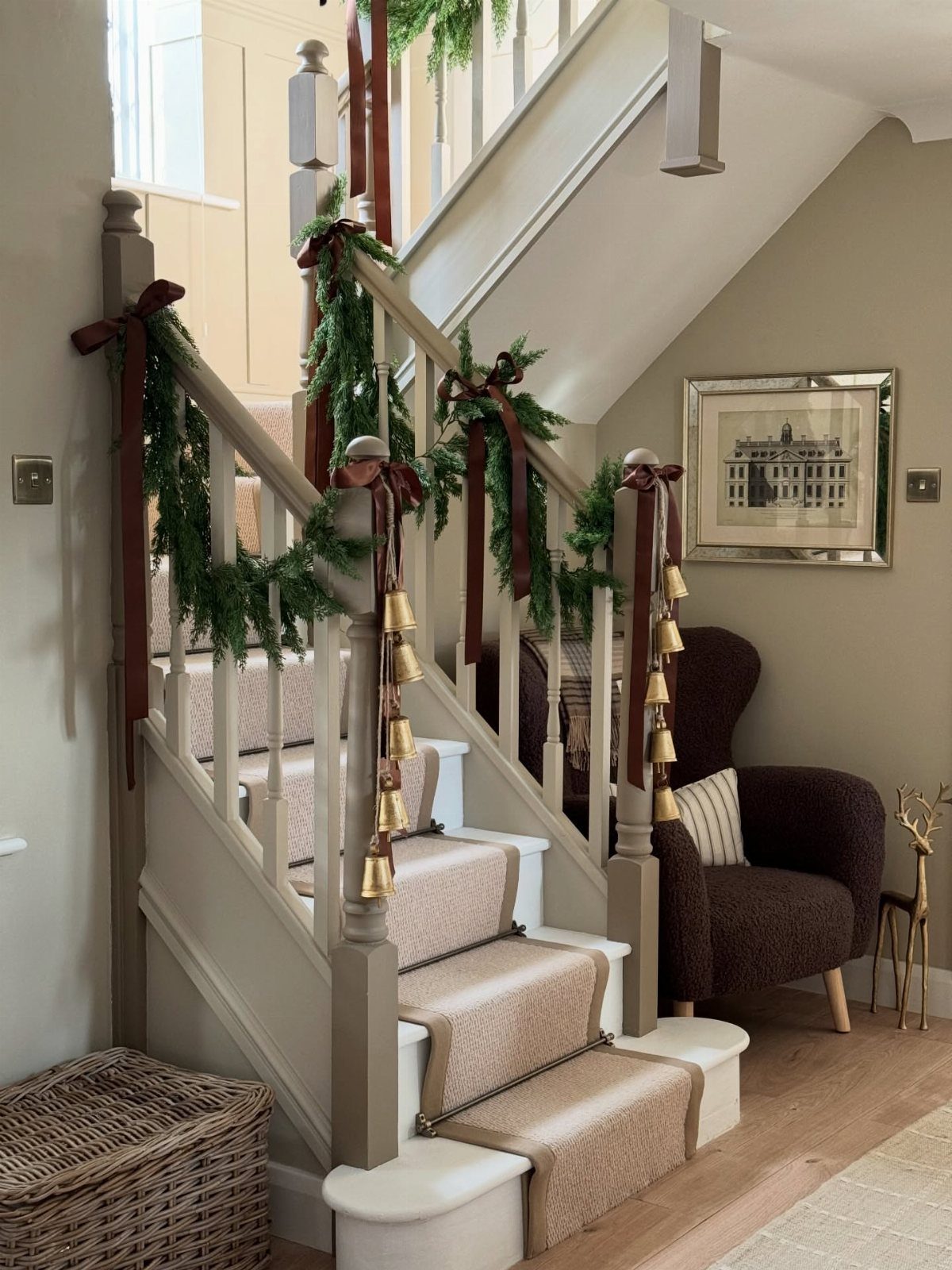 5 Christmas Stairs Decor Ideas: Garland, Bells, Paper Orbs & More 4 Christmas staircase decorated with green garlands, red ribbons, and hanging brass bells on the banister.