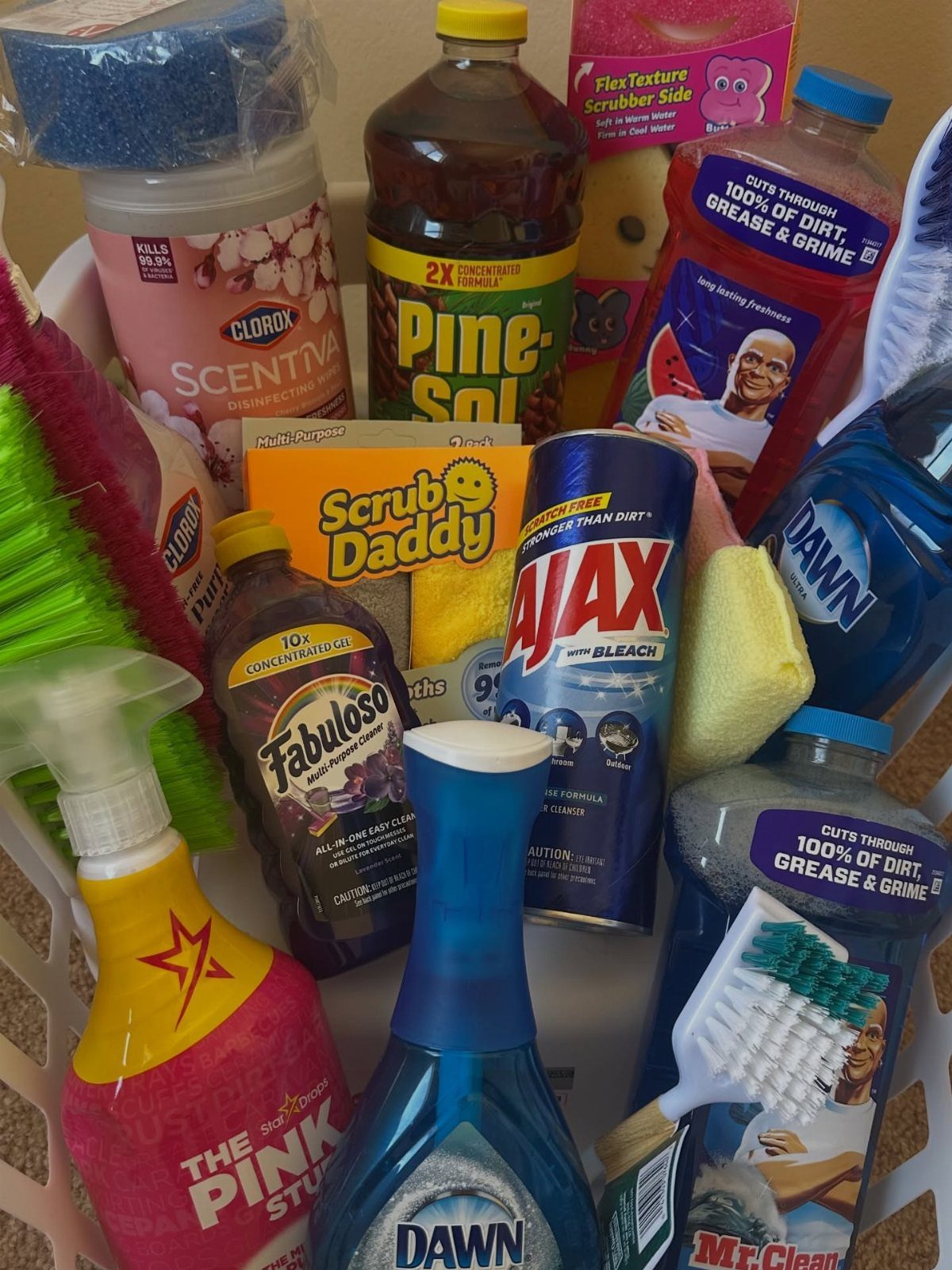 Cleaning Checklist by Room: 4 Lists That Actually Get Finished 4 A white basket overflowing with various colorful cleaning supplies like Pine-Sol, Ajax, and Dawn.