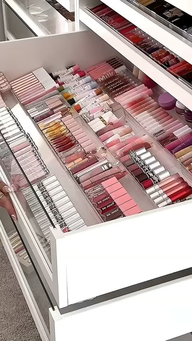 Lipsticks and lip glosses neatly arranged in rows within a white drawer organizer.