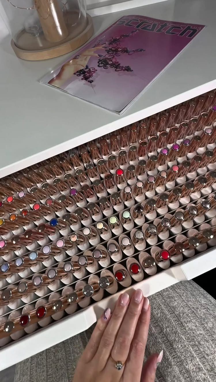 Rows of colorful nail polish bottles organized on a white tiered acrylic display riser.