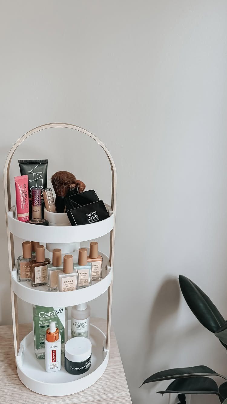 A white three-tiered circular cosmetic organizer holding nail polish, skincare, and makeup brushes.