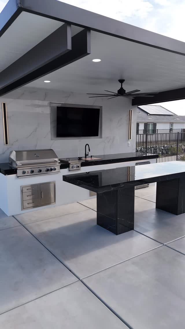 6 Covered Patio Grill Area Ideas for Any Yard 1 Modern outdoor kitchen with stainless steel grill and black countertops under a covered patio structure.