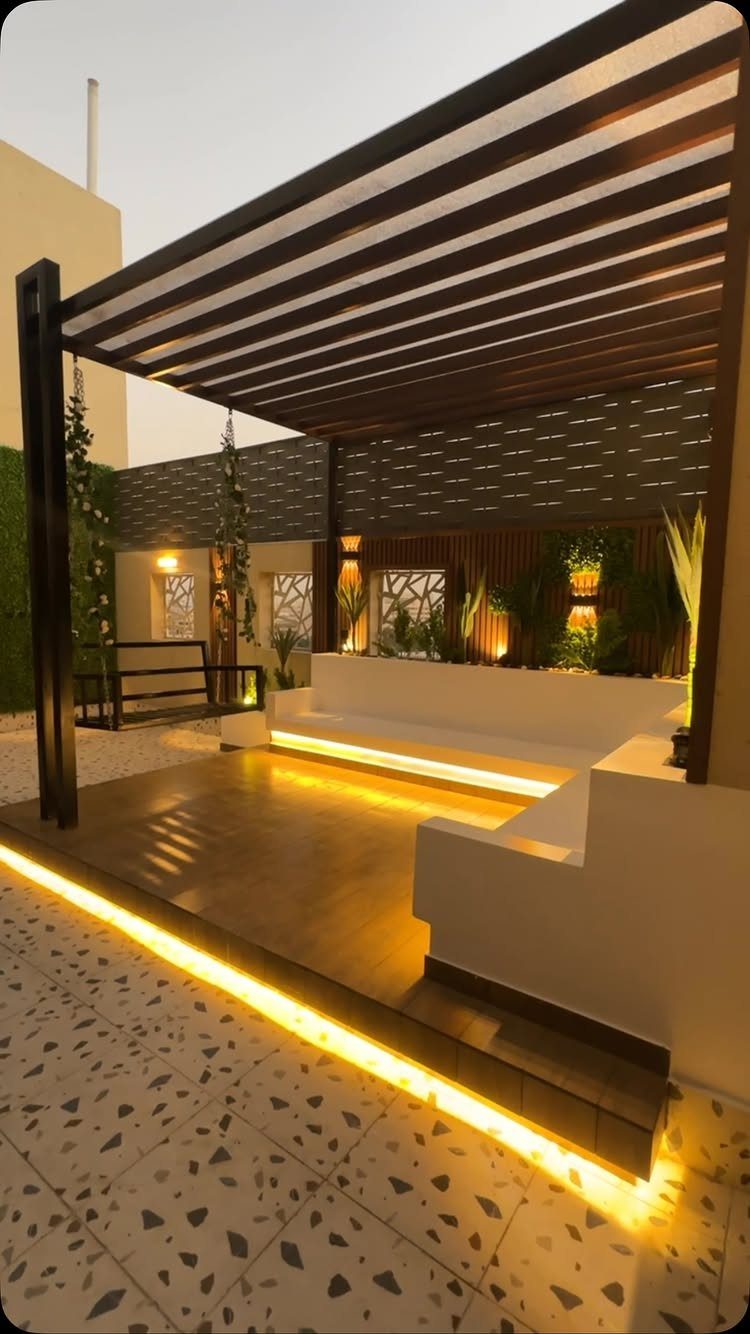 8 Deck No Railing Ideas for Outdoor Living without Barriers 2 Modern outdoor lounge with warm LED strip lighting under a dark wood pergola and white benches.