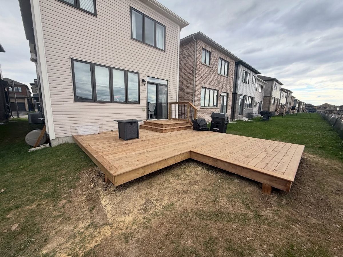 8 Deck No Railing Ideas for Outdoor Living without Barriers 1 L-shaped wooden ground-level deck without railings situated behind a residential house.