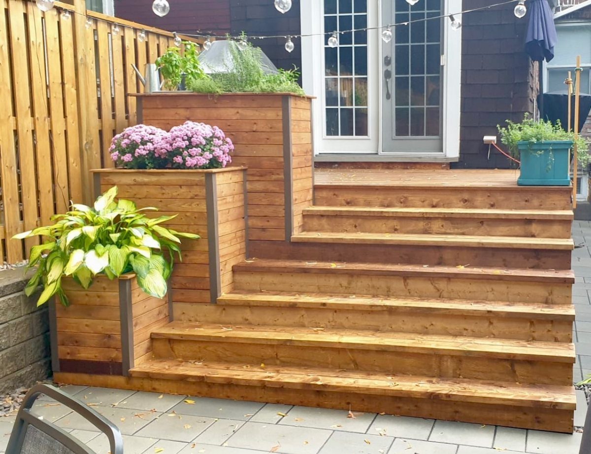 8 Deck No Railing Ideas for Outdoor Living without Barriers 7 Wooden deck steps featuring integrated planter boxes with pink and green plants as a boundary.