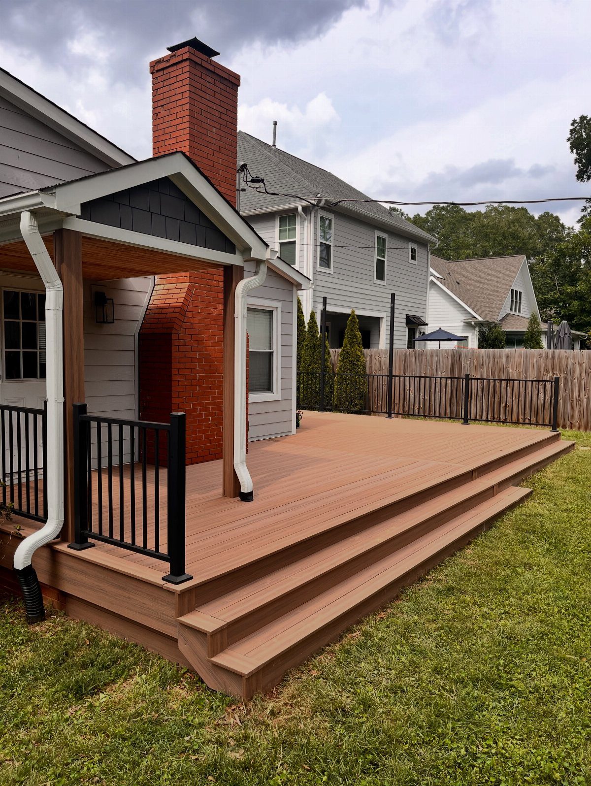 8 Deck No Railing Ideas for Outdoor Living without Barriers 5 A wide brown composite deck with large steps leading to a green grass lawn.
