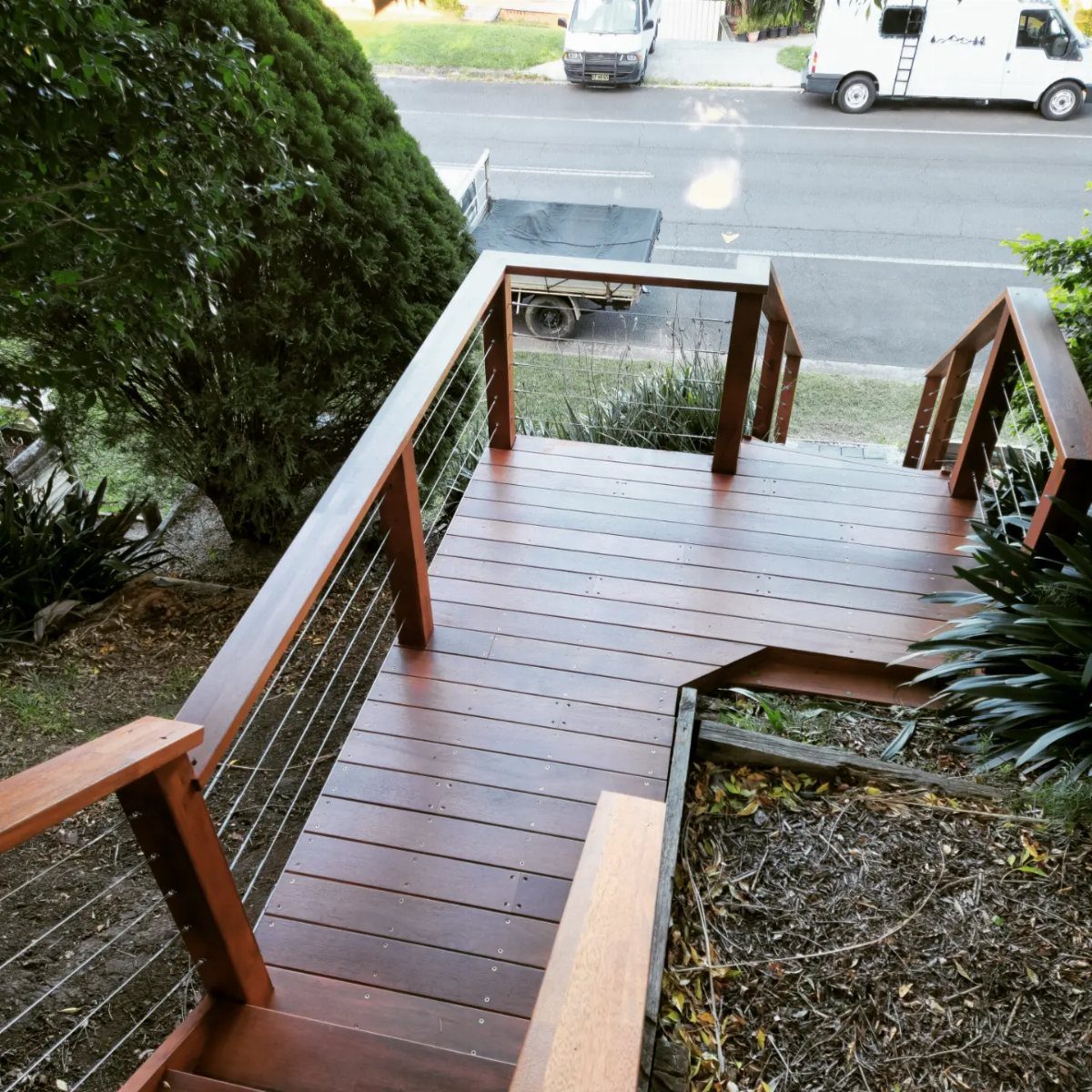 Deck on a Slope: 5 Ideas That Beat the Grade 4 Wooden deck with cable railings built on a sloped garden area overlooking a street.