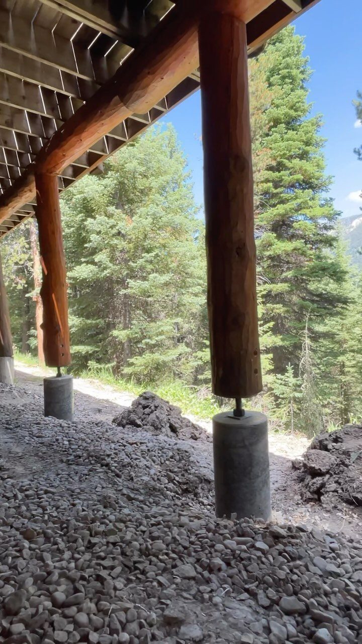 Deck on a Slope: 5 Ideas That Beat the Grade 5 Wooden log posts resting on concrete footings supporting a deck above a gravel slope.