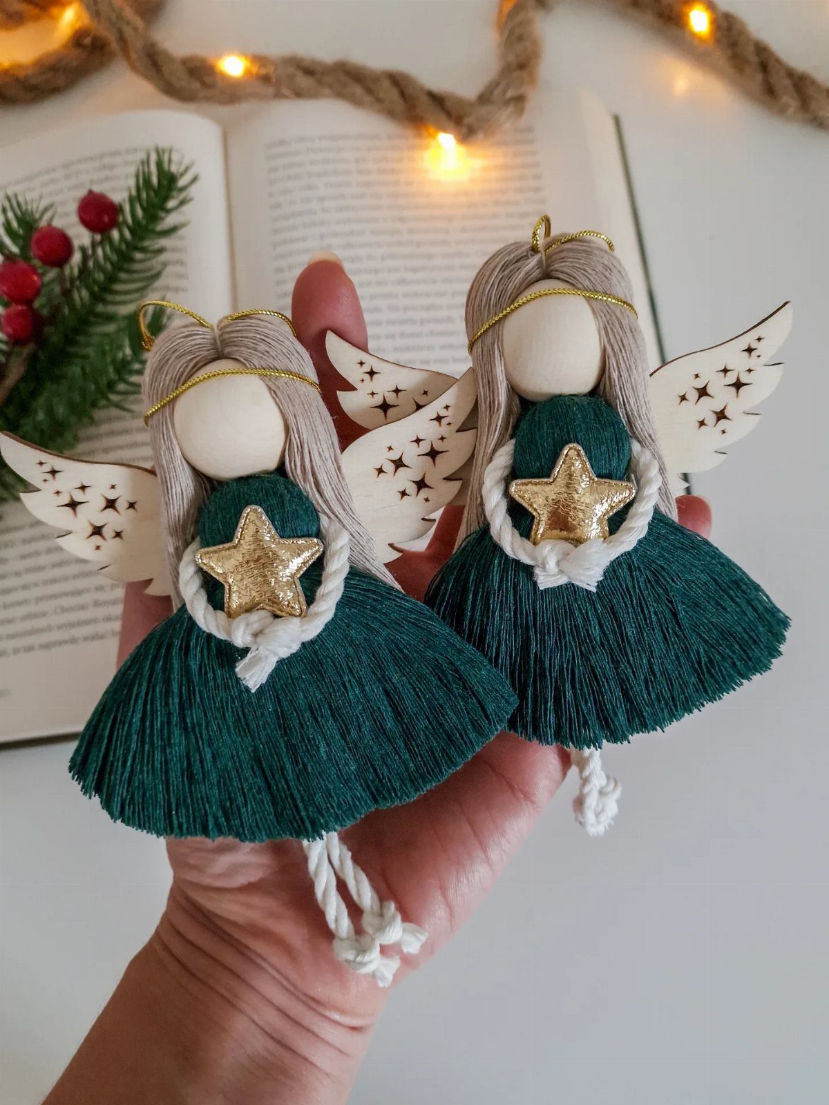 21 DIY Christmas Ornaments for Adults 14 Two handmade angel ornaments with green yarn dresses and gold stars held in a hand.