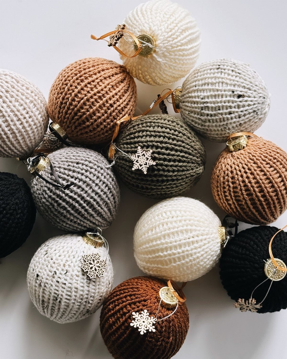 21 DIY Christmas Ornaments for Adults 10 Yarn-wrapped spherical Christmas ornaments in neutral colors scattered on a white background.