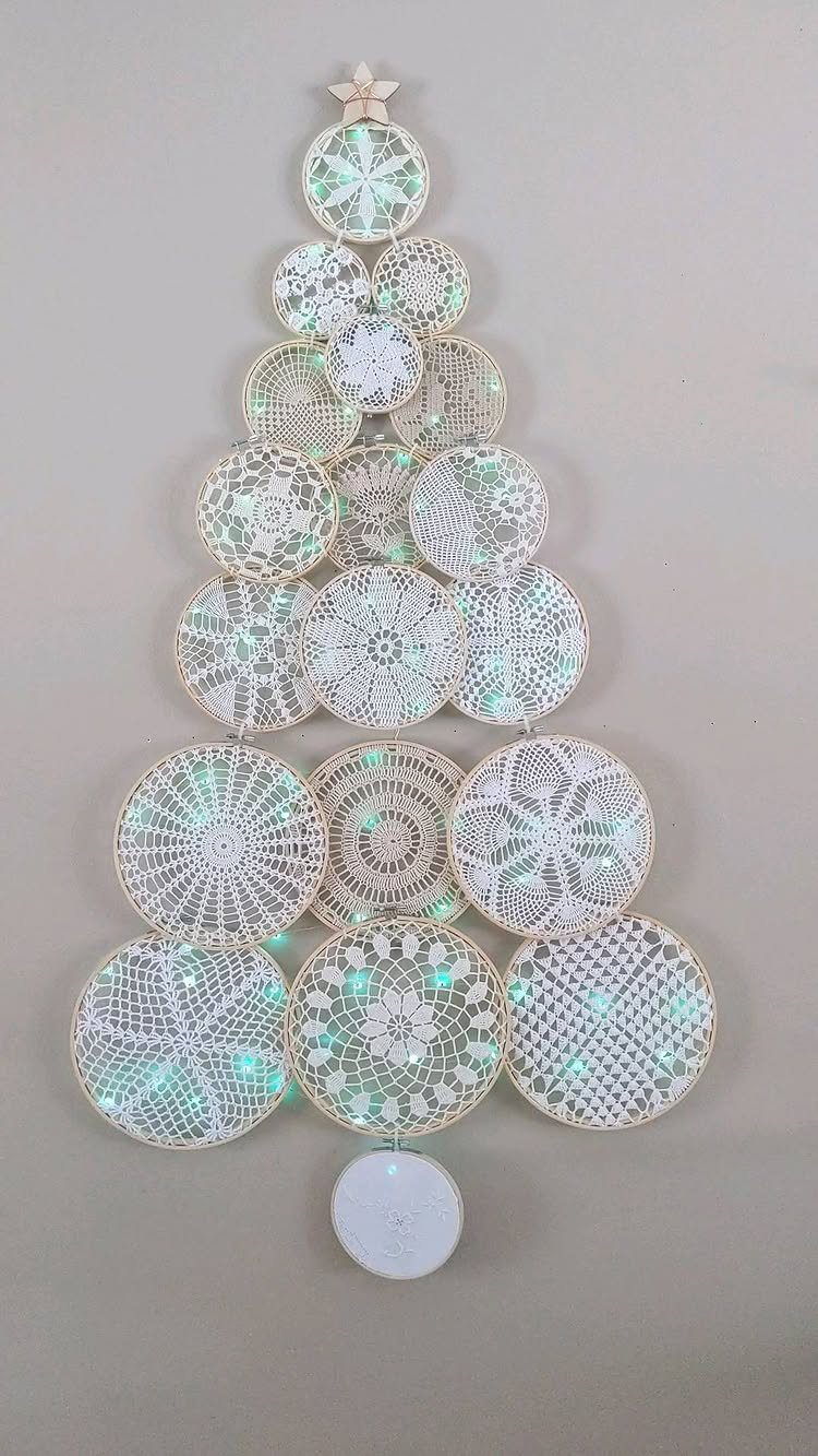 21 DIY Christmas Ornaments for Adults 15 White lace doilies arranged on a wall in the shape of a Christmas tree.