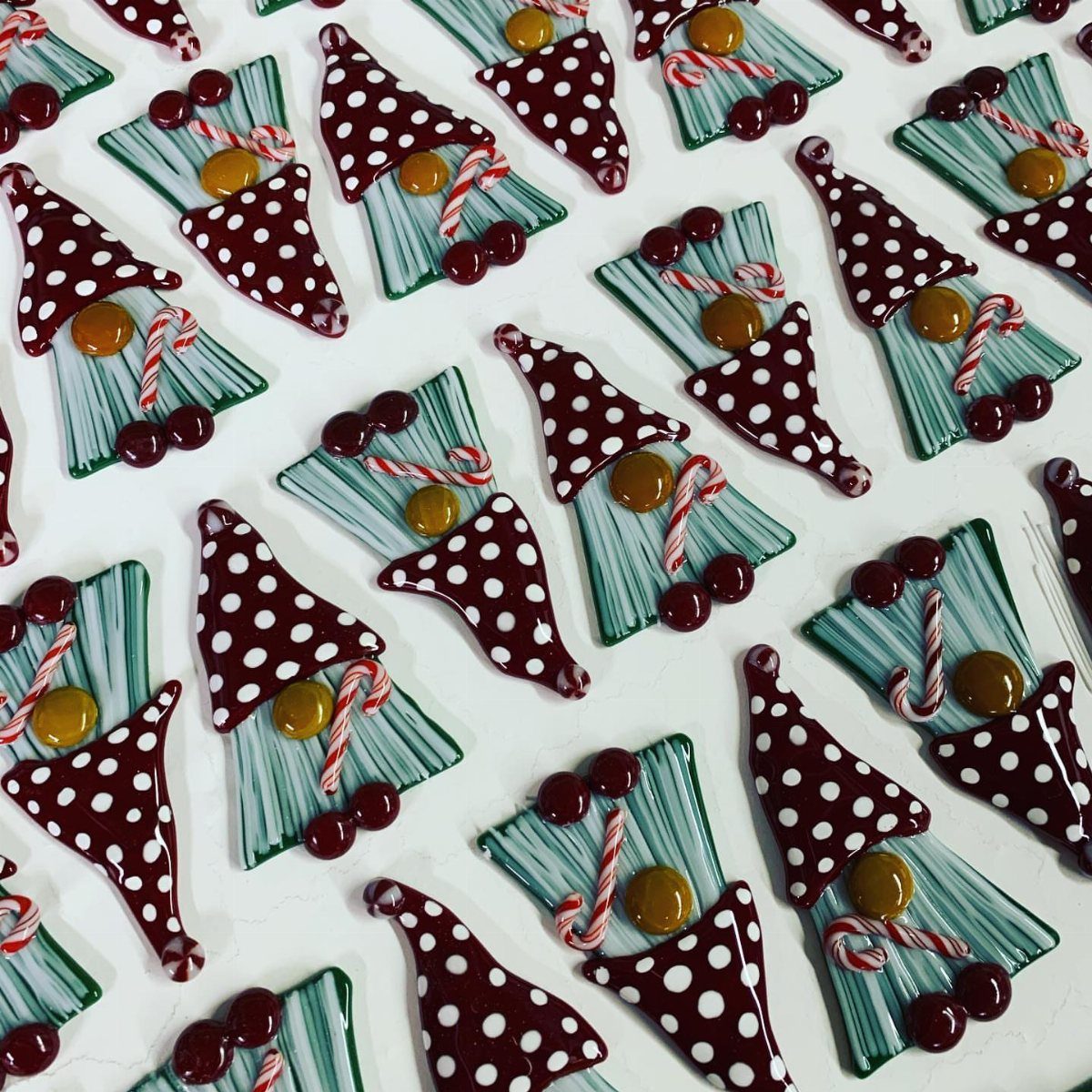 21 DIY Christmas Ornaments for Adults 9 Handmade gnome ornaments with maroon polka-dot hats and teal striped bodies on a white background.