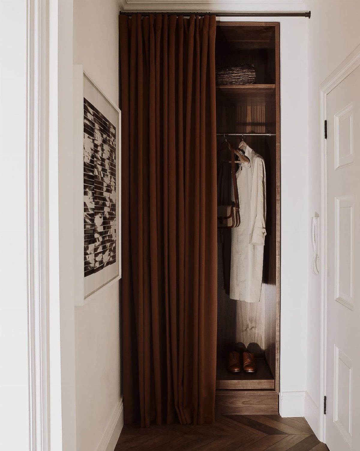 10 DIY Closet Ideas for Room With No Closet 4 Brown curtain partially covering a wooden built-in closet with white clothing and shoes.