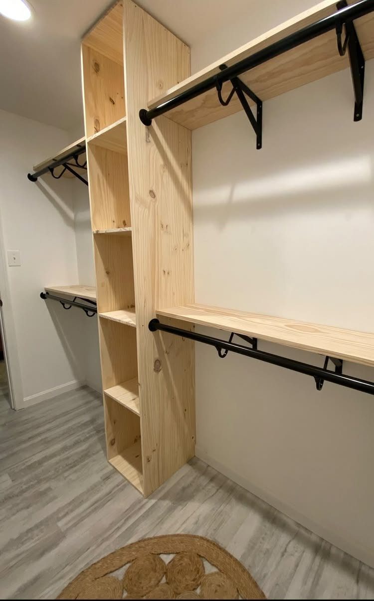 10 DIY Closet Ideas for Room With No Closet 5 Custom wooden shelving unit with black clothing rods installed against a white wall.