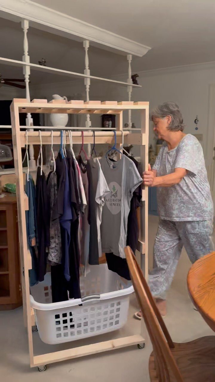 10 DIY Closet Ideas for Room With No Closet 10 A wooden rolling clothing rack holding various shirts with a laundry basket underneath.