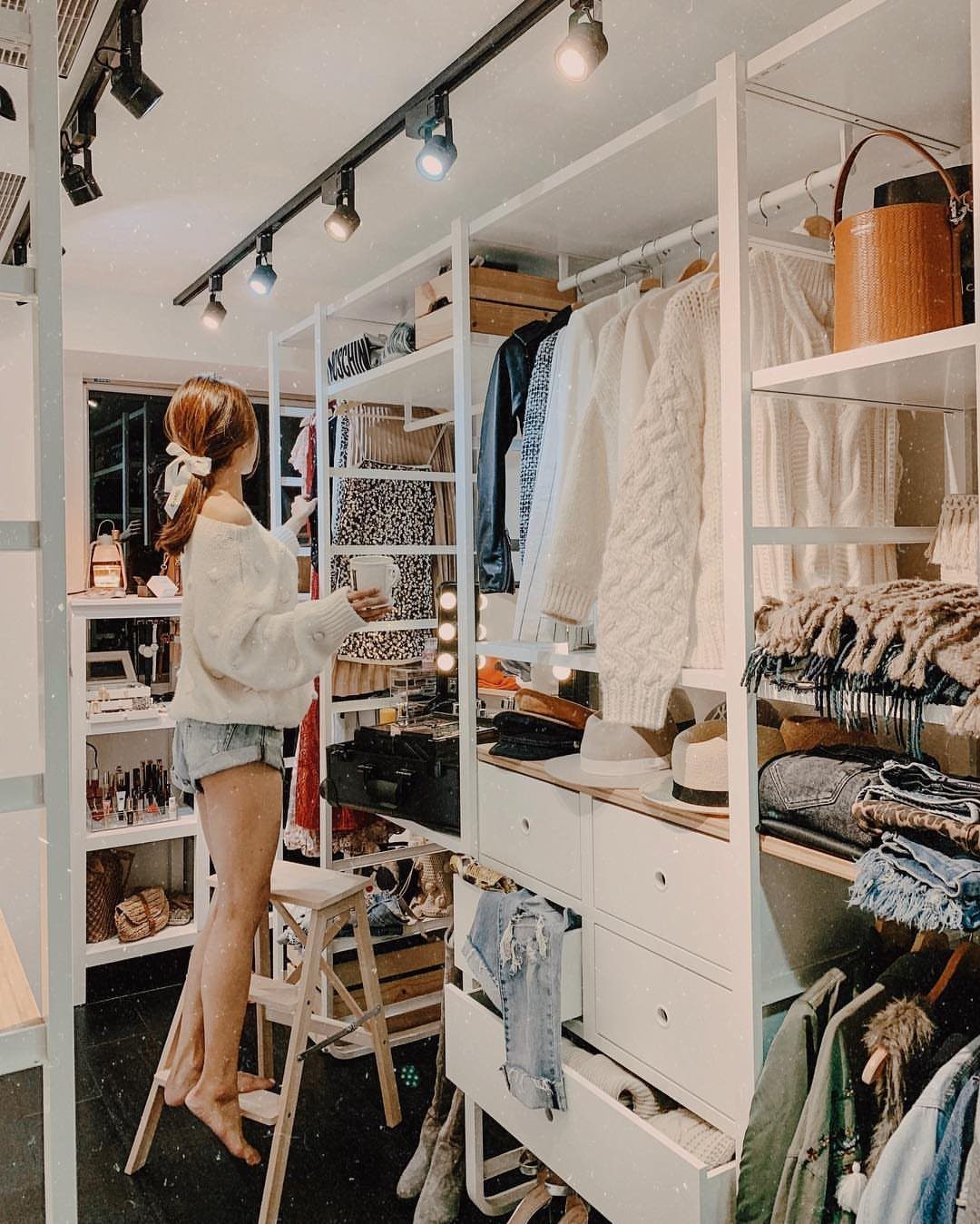 5 DIY Closet Upgrade Ideas Using Popular Wall and Modular Systems 5 A woman stands in a white modular walk-in closet system filled with clothes and drawers.