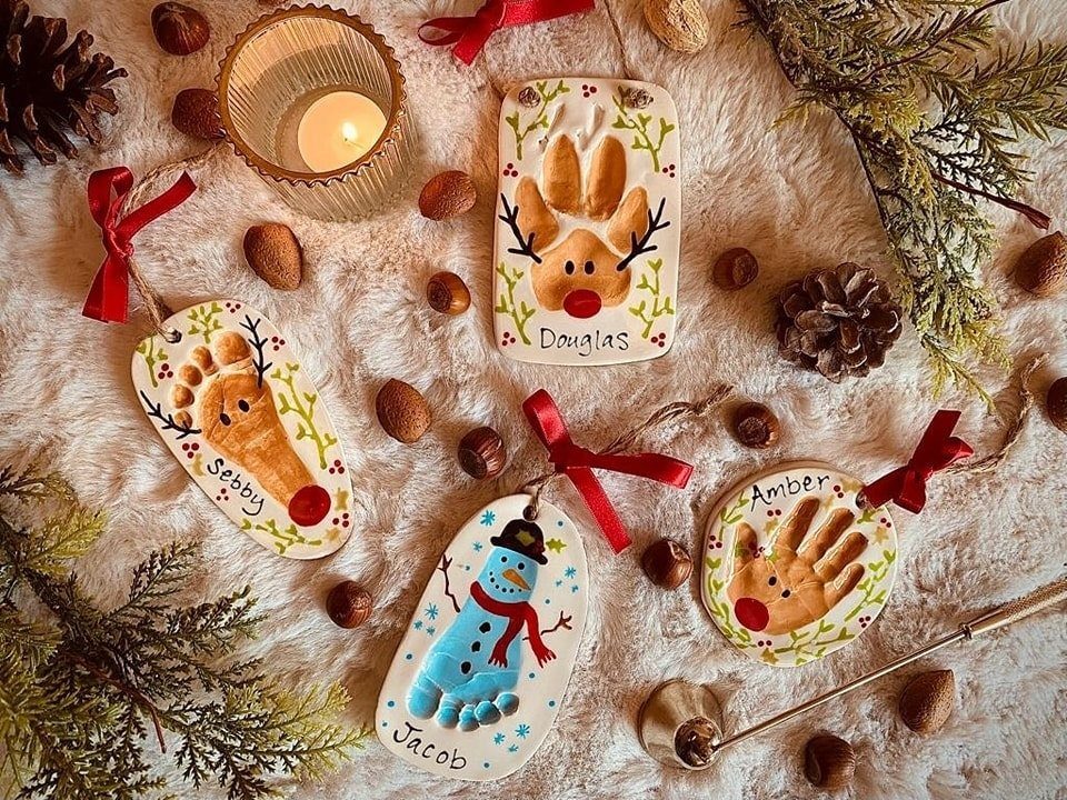 Easy Christmas Clay Ideas: 9 Projects for Handmade Ornaments 3 Four handmade clay ornaments with colorful fingerprint designs and names resting on white faux fur.