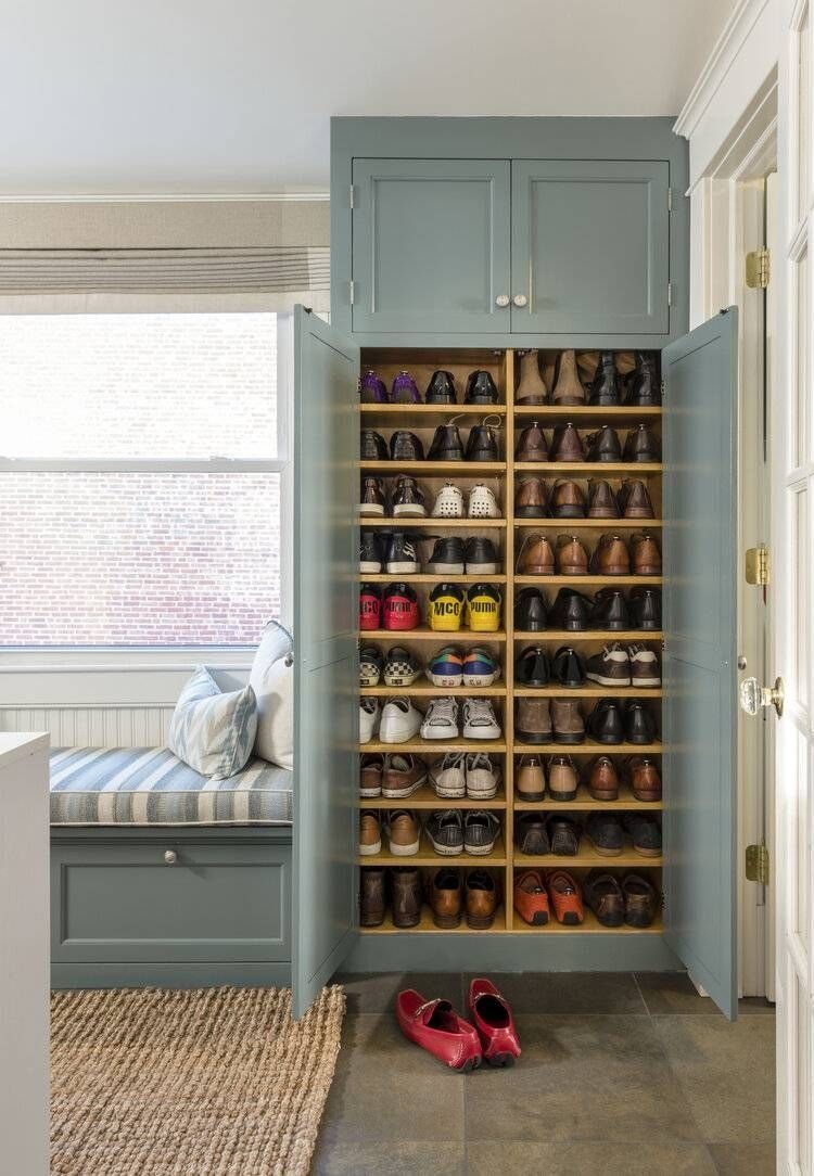 Full Height Shoe Rack Design with Seating: 6 Entryway Ideas 5 Open light blue built-in cabinet displaying many rows of organized shoes on wooden shelves.