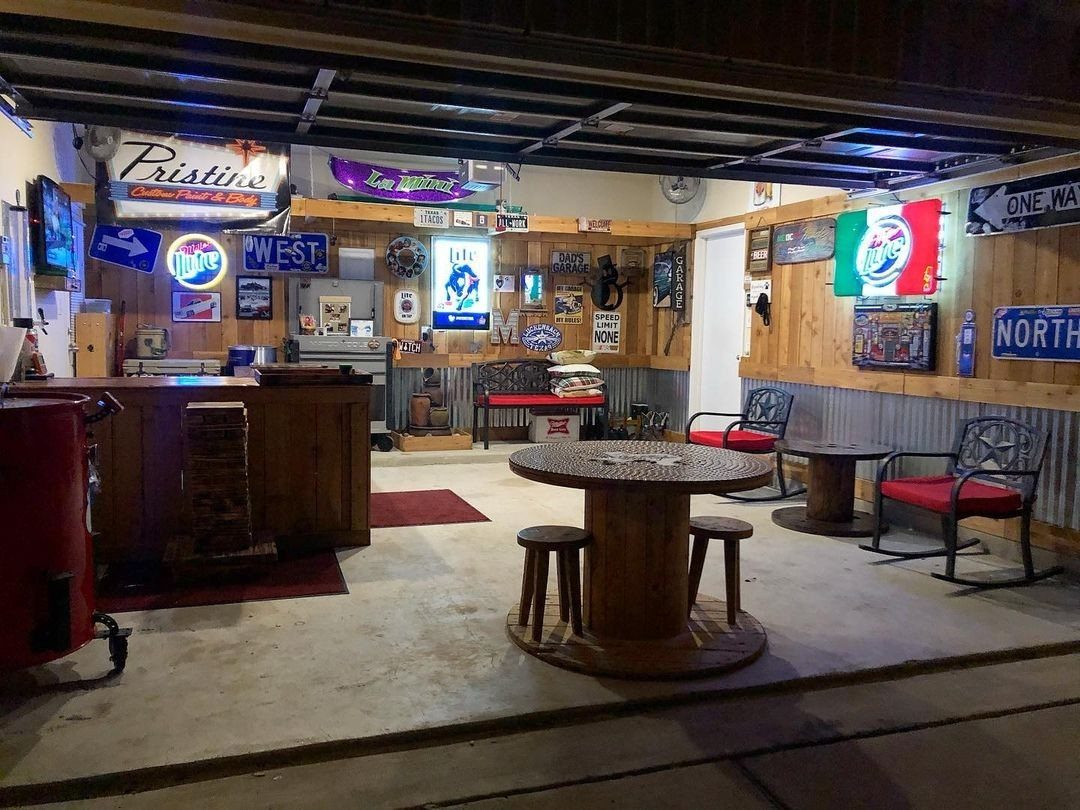 A garage converted into a rustic bar with wooden furniture and neon signs.